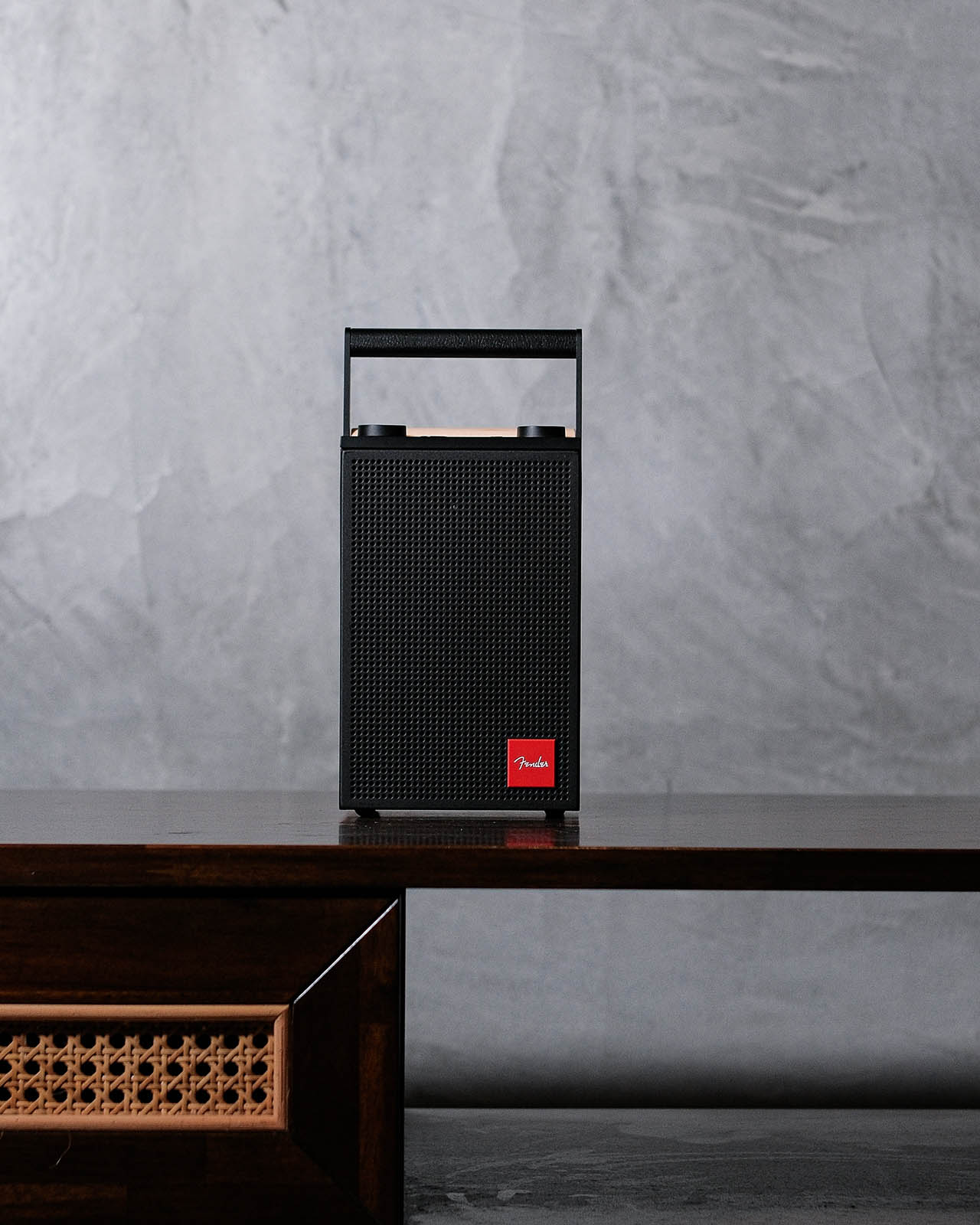 Fender Elie 6 Skyscraper Black trên kệ gỗ: lưới kim loại, panel gỗ phong và quai da kiểu ampli Fender