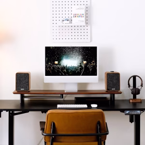 Bàn đứng đen với iMac, hai loa gỗ, bàn phím chuột Apple, tai nghe, ghế da và pegboard sách Dentsu