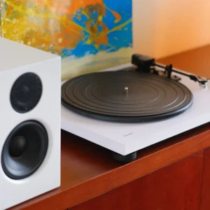 Mâm đĩa than TEAC TN-180BT-A3 trắng và loa bookshelf Audio Pro A28W trên kệ gỗ, khung cảnh phòng khách