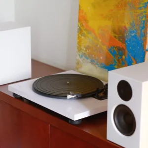 Combo máy nghe nhạc đĩa than TEAC TN-180BT-A3 và loa bookshelf Audio Pro A28W màu trắng trên kệ gỗ sẫm, tranh abstract vàng cam xanh