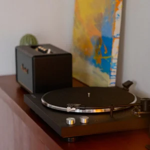 Mâm đĩa than Kanto OBI3 và loa Marshall Acton III trên kệ gỗ ấm, tranh abstract phía sau