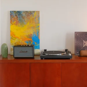 Combo dàn âm thanh gồm mâm đĩa than Kanto OBI3 và loa Marshall Acton III đặt trên kệ gỗ cạnh tranh trừu tượng