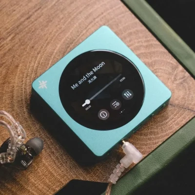 FiiO SnowSky DISC màu ngọc trên gỗ với tai IEM trong suốt, màn hình tròn hiển thị bài hát và thanh tiến trình