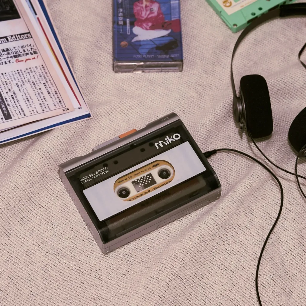 Gadhouse Miko máy cassette wireless stereo flatlay trên vải be, tai nghe retro, tạp chí và băng cassette xung quanh