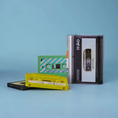 Gadhouse Miko màu bạc trên nền xanh nhạt cùng băng cassette nhiều màu, ảnh sản phẩm studio phong cách retro