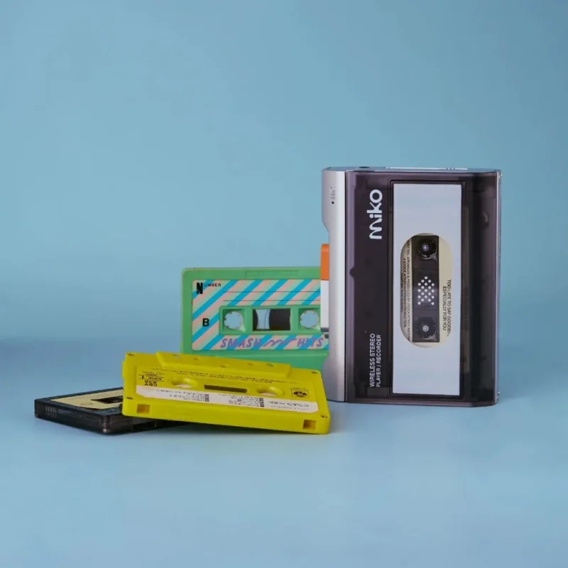 Gadhouse Miko màu bạc trên nền xanh nhạt cùng băng cassette nhiều màu, ảnh sản phẩm studio phong cách retro