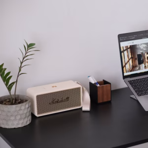 Loa Bluetooth Marshall màu kem cạnh laptop hiển thị trang chủ District M