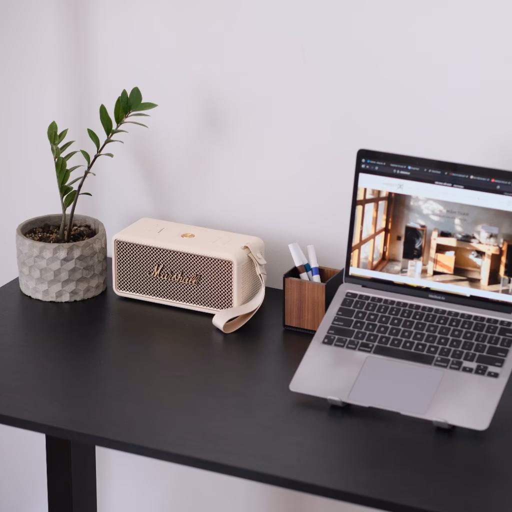 Loa Marshall portable, cây cảnh, hộp bút và laptop trên bàn làm việc