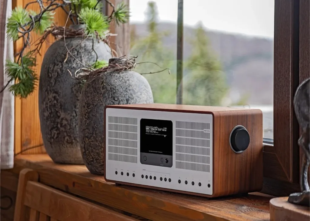 Revo SuperConnect Stereo Internet radio walnut trên bệ cửa sổ gỗ, bình trang trí và cảnh ngoài trời mờ phía sau