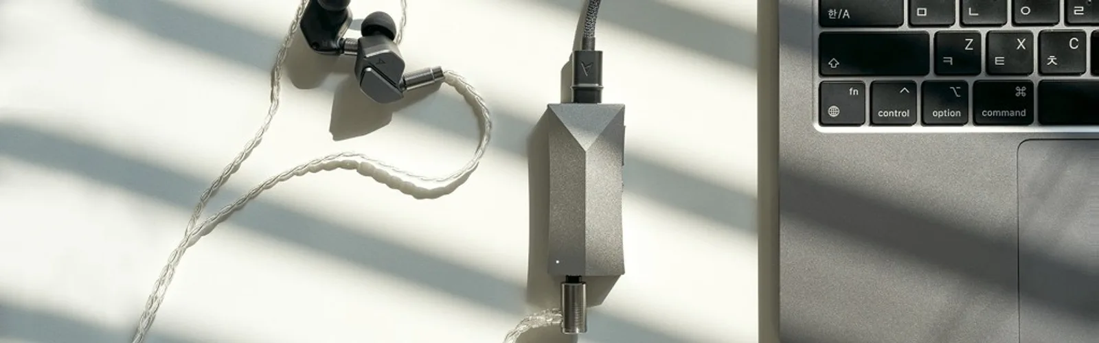 AK HC4 bạc trên bàn sáng: nối laptop USB-C, IEM dây bạc, LED trạng thái; thiết kế góc cạnh ánh sáng bóng râm rèm.