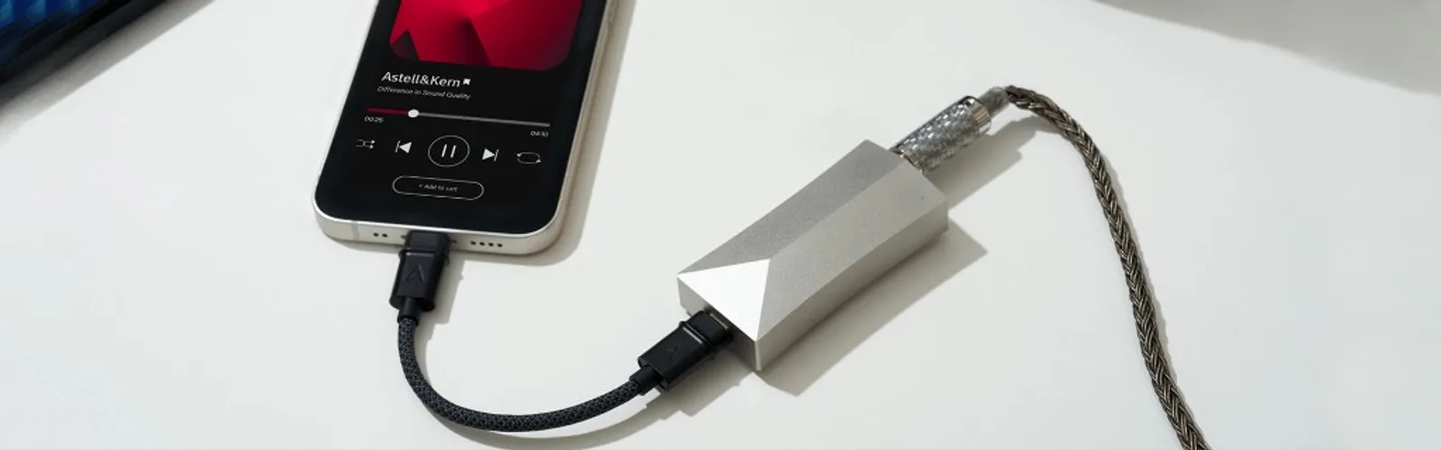 Astell&Kern AK HC4 bạc nối iPhone qua cáp USB-C và tai nghe dây đồng; màn hình hiển thị app Astell&Kern Difference in Sound Quality trên nền trắng.