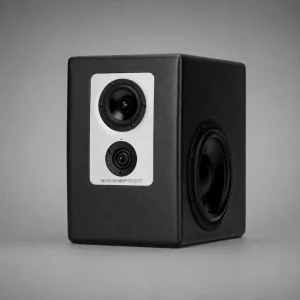 Barefoot Footprint01 góc ba phần tư: mặt trước plate trắng với mid, tweeter dual-ring, LED xanh lá giữa hai driver, chữ BAREFOOT; cạnh phải woofer bắn ngang với ốc quanh vành; thùng đen vân sần, nền xám trung tính, bóng đổ nhẹ
