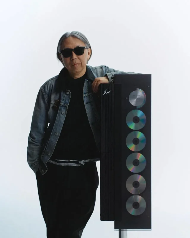 Hiroshi Fujiwara đứng cạnh Beosystem 9000c Fragment Edition đen với logo tia sét và 6 đĩa CD