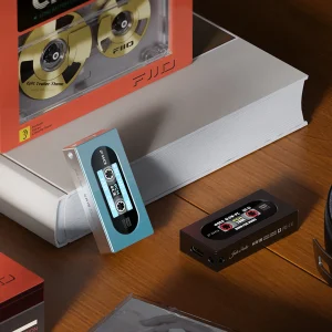 Hai DAC/Amp FiiO KA15 màu xanh ngọc và đen trên bàn gỗ, màn hình LCD hiển thị giao diện băng cassette cổ điển