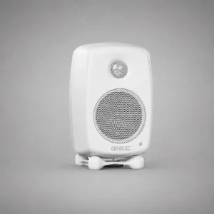 Genelec G One màu Polar White: thùng MDE bo tròn mờ trắng, tweeter và woofer lưới kim loại trắng, logo GENELEC xám nhạt, LED trạng thái, chân Iso-Pod trắng bốn chấm; ảnh sản phẩm studio nền xám trung tính, góc ba phần tư