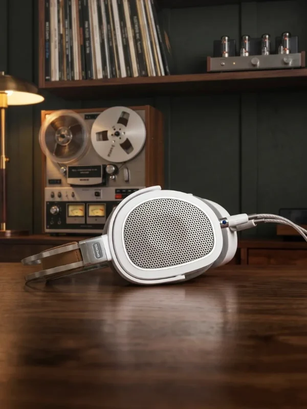 Tai nghe Koss A/550 trắng bạc đặt cạnh máy băng cổ, cáp dệt và phòng nghe vinyl