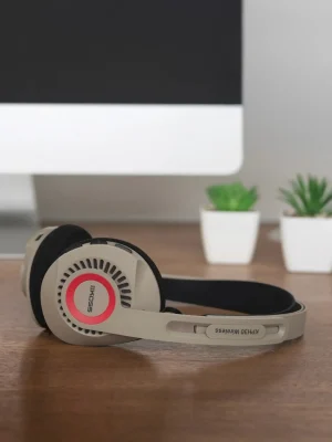 Tai nghe Koss KPH30 Wireless màu beige trên bàn gỗ, viền đỏ logo KOSS và nút điều khiển trên chụp tai
