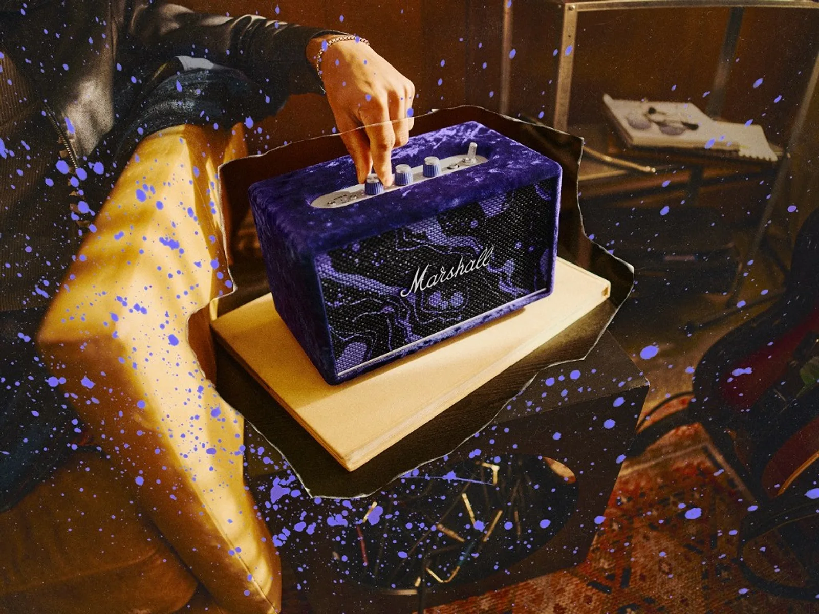 Loa Marshall Acton III phiên bản Hendrix: thân bọc nhung tím, grille họa tiết tím-trắng, logo Marshall script; tay chỉnh núm bạc trên nắp kim loại, hiệu ứng splatter tím và hạt phim trên khung hình, nền phòng retro