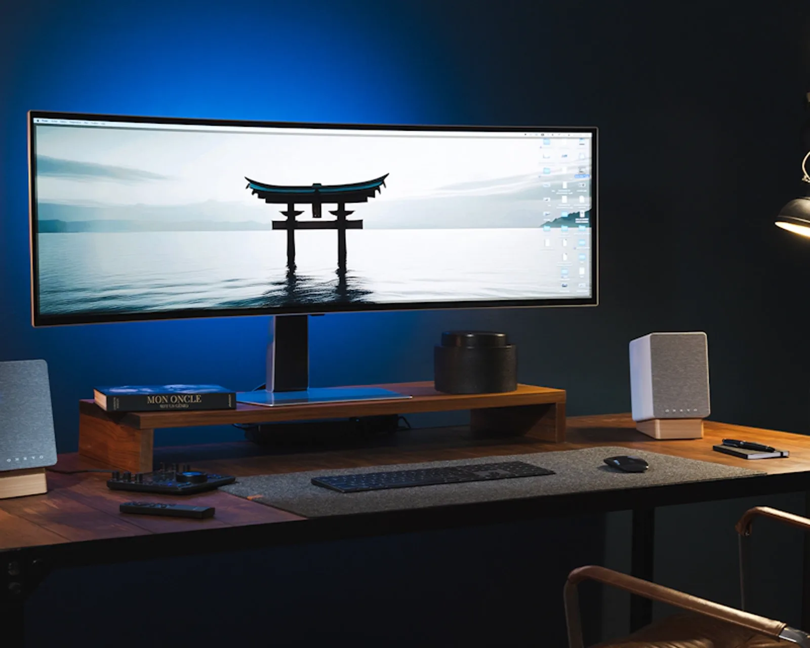 Cặp loa Onkyo Creator GX-10DB hai bên màn ultrawide, bàn phím và đèn bàn trong không gian làm việc