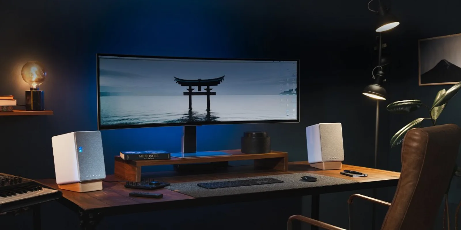 Cặp loa Onkyo Creator GX-30ARC trắng trên bàn gỗ với màn ultrawide, đèn ấm và phòng xanh đậm