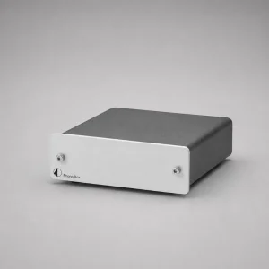 Pro-Ject Phono Box DC: hộp phono preamp vỏ đen, mặt trước nhôm bạc với 2 ốc, logo Pro-Ject và chữ Phono Box, nền xám studio