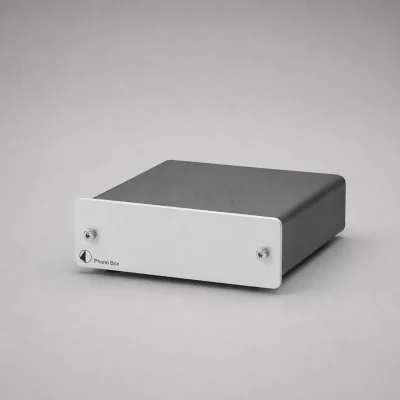 Pro-Ject Phono Box DC: hộp phono preamp vỏ đen, mặt trước nhôm bạc với 2 ốc, logo Pro-Ject và chữ Phono Box, nền xám studio