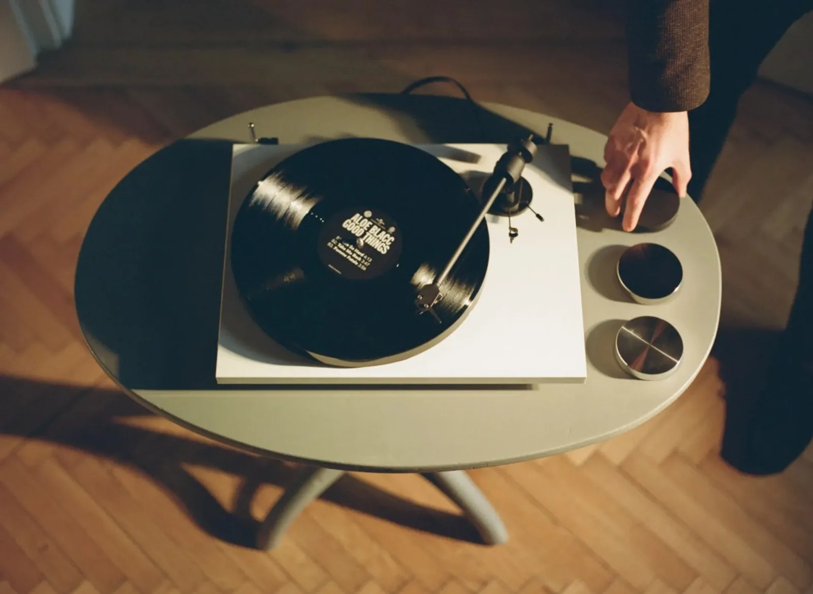Ba puck Pro-Ject Record Puck E đen và bạc cạnh máy quay trắng, đĩa Aloe Blacc