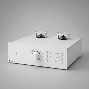 Pro-Ject Tube Box DS2: phono preamp đèn vỏ nhôm bạc lớn, có hai bóng đèn lộ thiên trên nóc, núm xoay lớn chỉnh loading ở mặt trước cùng các nút input/output, subsonic, gain và thông số loading, nền xám studio