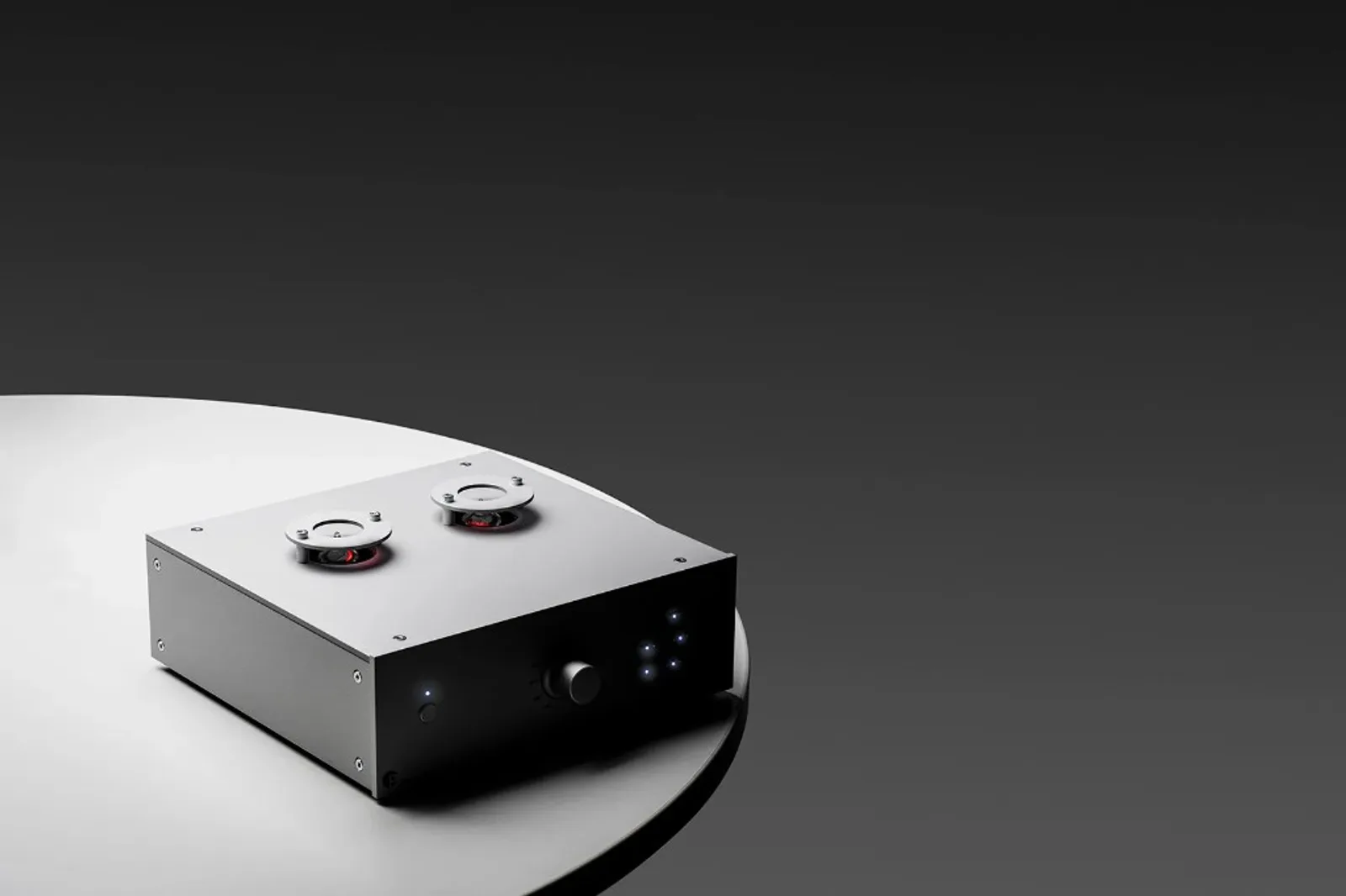 Pro-Ject Tube Box DS3 B đặt trên bàn tròn trắng, máy màu đen với hai bóng đèn trên nóc và đèn báo mặt trước, nền tối