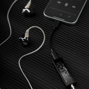 Minh họa Questyle M12i: bên trái nối laptop qua USB-C, bên phải nối iPad đang phát nhạc với tai nghe in-ear — DAC/Amp di động jack 3,5 mm cho máy tính và máy tính bảng.