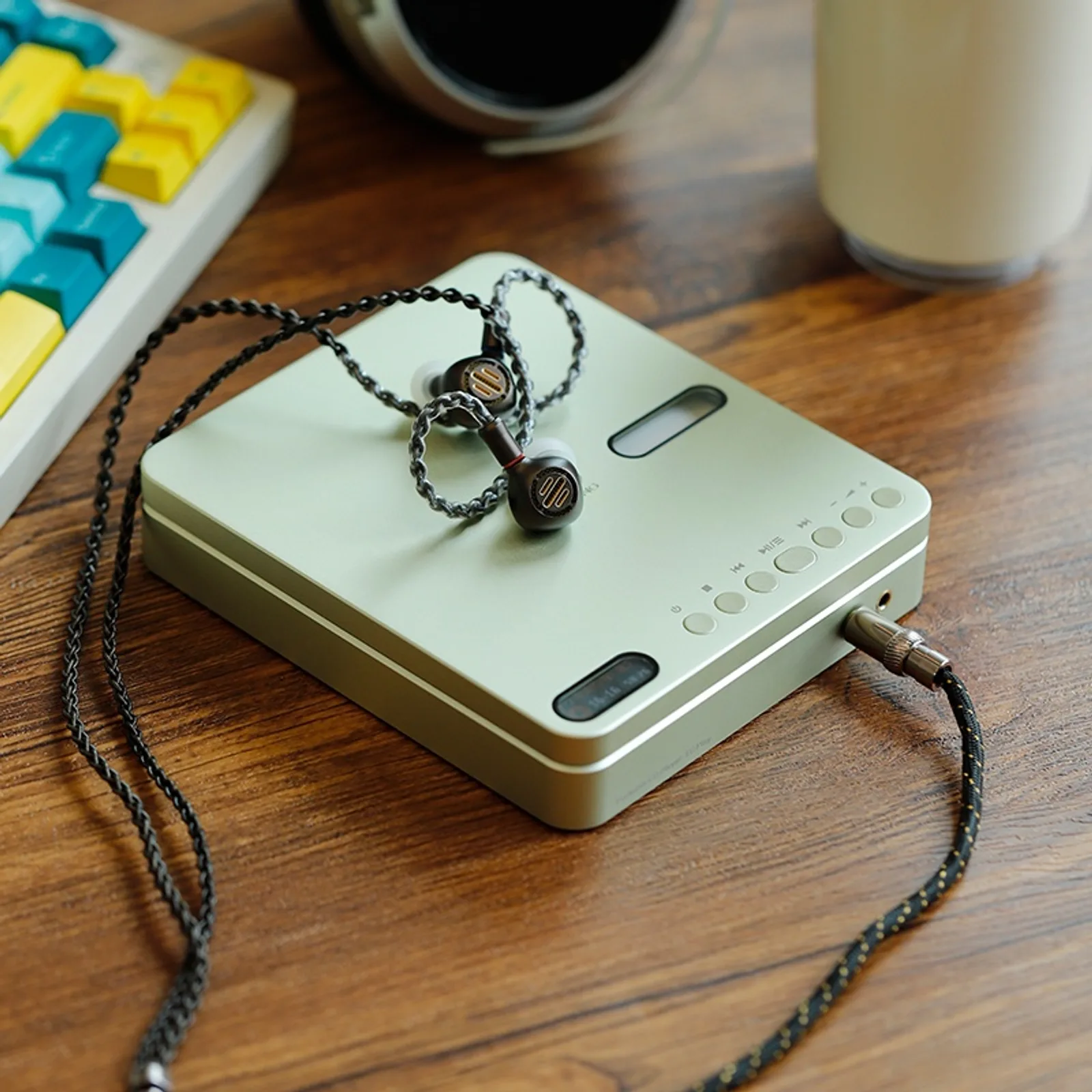 Shanling EC Play màu xanh mint trên bàn gỗ kèm IEM và cáp braided, tai nghe over-ear phía sau
