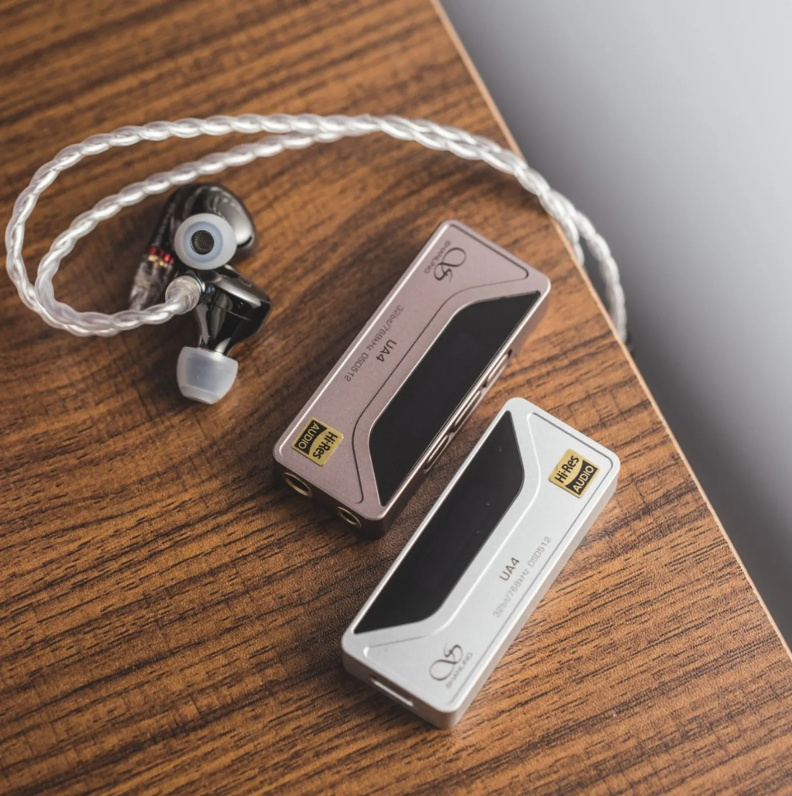 Cận cảnh Shanling UA4 bạc/champagne: màn OLED volume 91, PCM 48 kHz, logo Hi-Res, UA4, 32bit/768kHz DSD512, cáp USB-C và jack tai nghe trên trang sách.