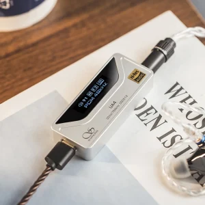 Shanling UA4 màu champagne trên sách: màn OLED hiển thị volume 91, gain H, filter F2, PCM 48 kHz; logo Hi-Res, chữ 32bit/768kHz DSD512, cổng USB-C và jack tai nghe.