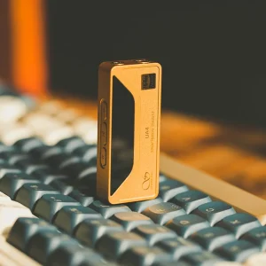 Shanling UA4 vàng đứng trên keycap bàn phím cơ: màn OLED, nút điều khiển bên hông, jack 3,5 mm và 4,4 mm phía trên, logo Hi-Res và Shanling.