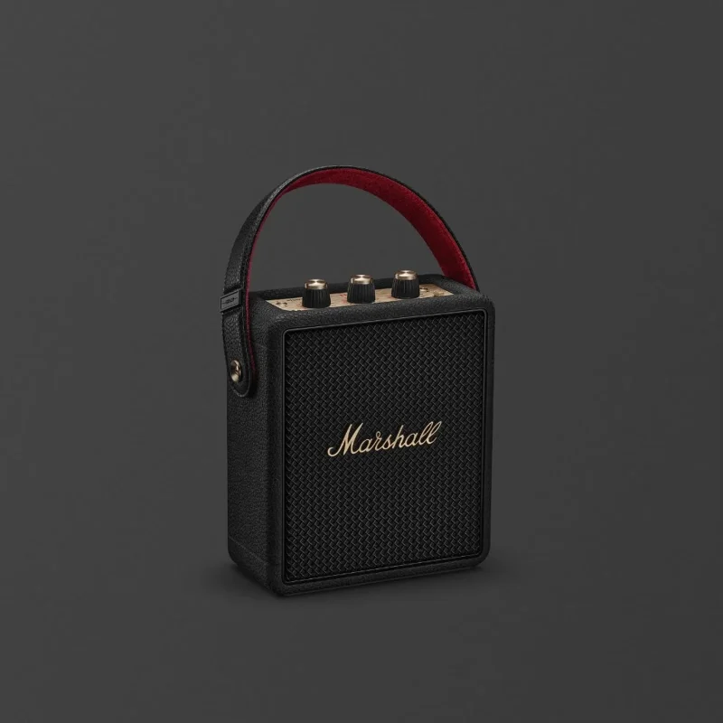 Loa Bluetooth Marshall Stockwell III đen với logo đồng, lưới loa và dây đeo đỏ trên nền xám