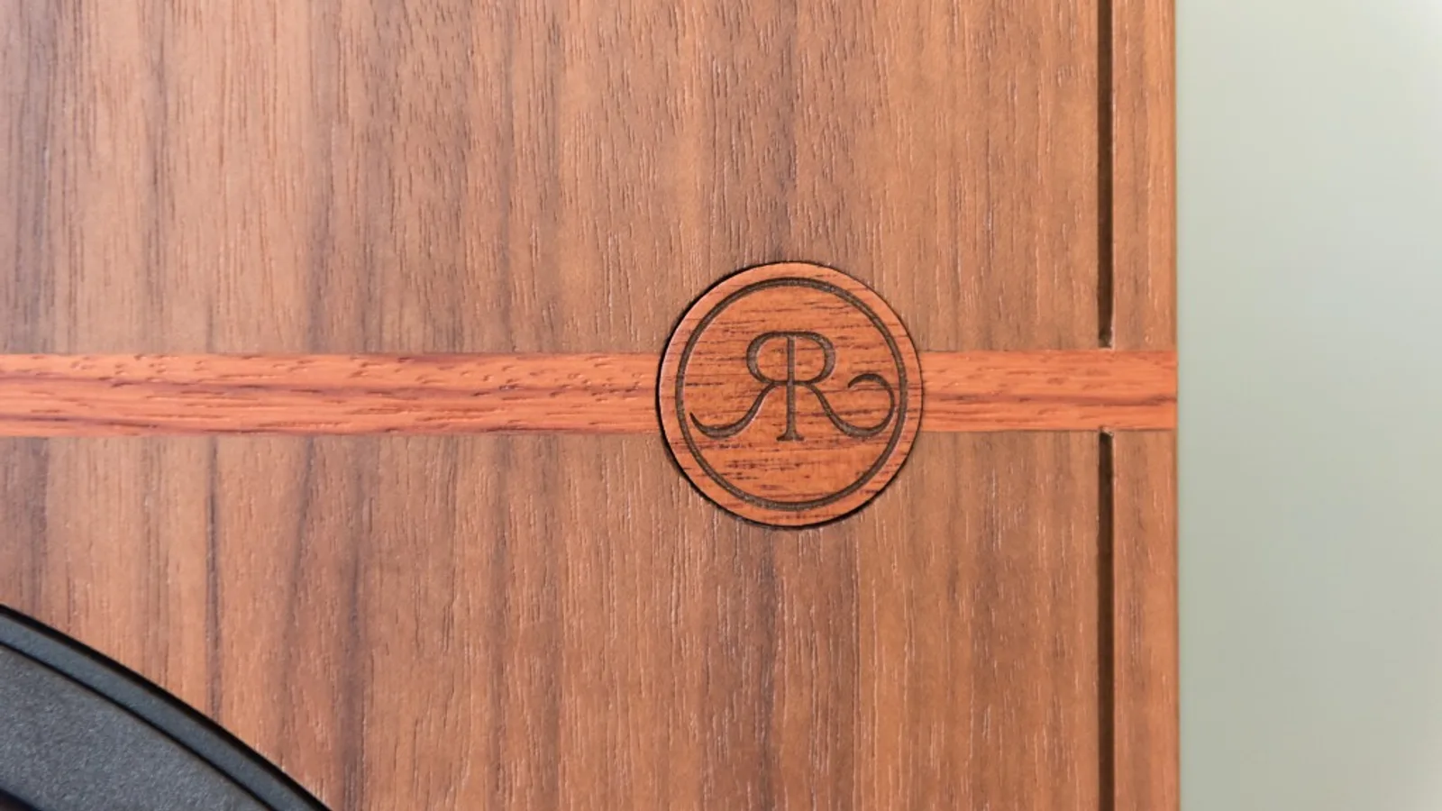 Cận cảnh logo Revival Audio chạm trên thùng loa ATALANTE 3 vân gỗ walnut và đường chỉ trang trí