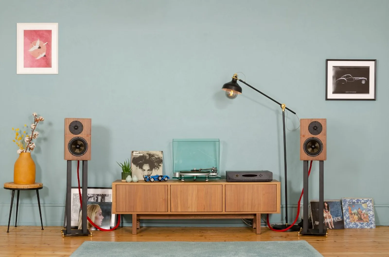 Cặp loa Revival Audio ATALANTE 3 trên chân loa dây loa đỏ hai bên kệ nghe nhạc tường xanh phòng khách