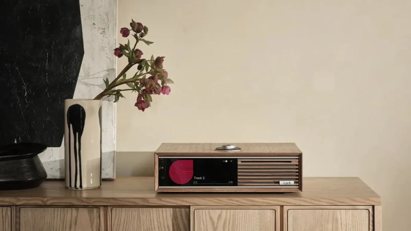 Ruark R710 trên kệ gỗ trong phòng khách, màn phát nhạc, RotoDial trên mặt trên, decor tối giản
