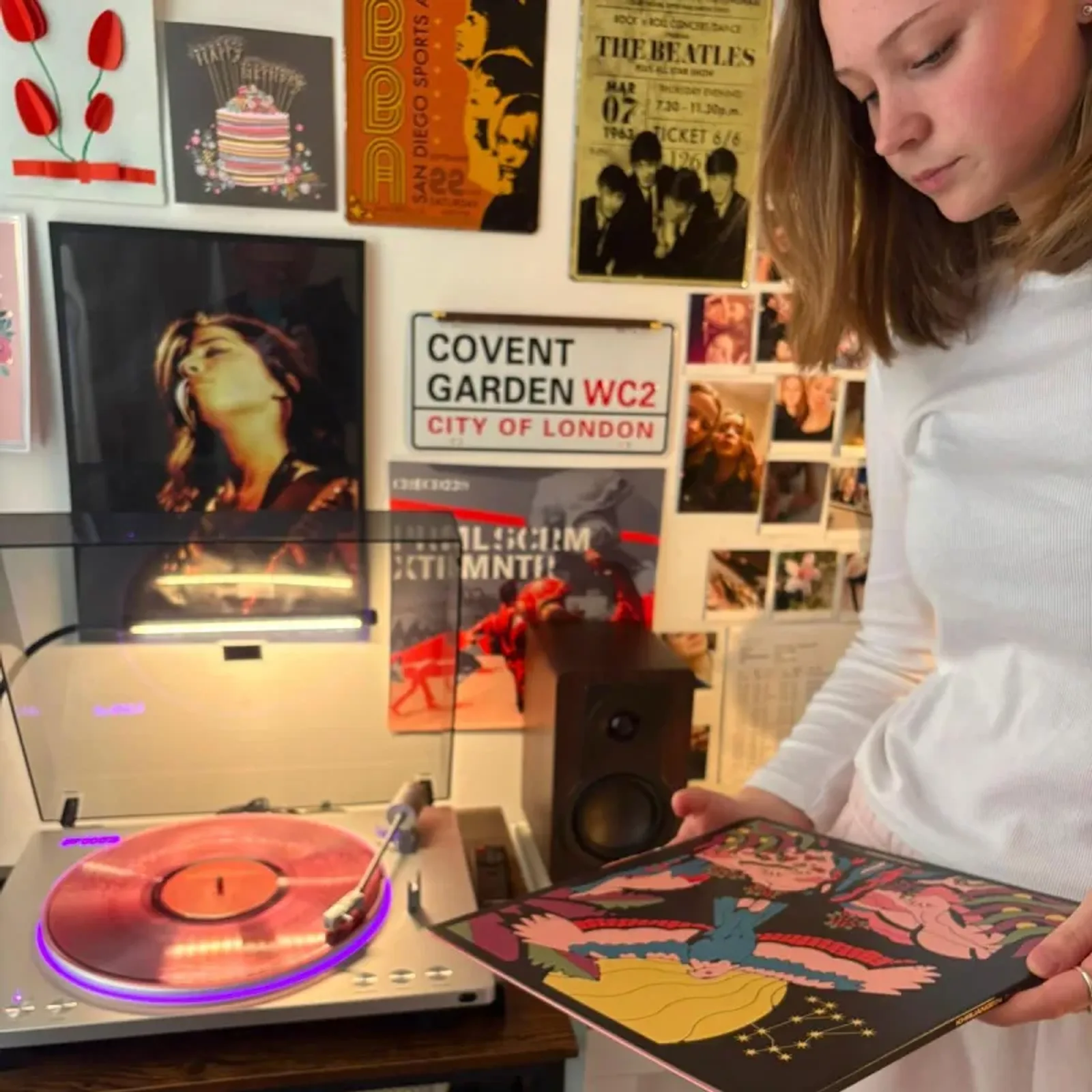 Người trẻ nghe vinyl cạnh loa DALI KUPID Dark Walnut và mâm đĩa than trong phòng trang trí poster