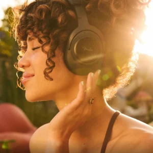 Tai nghe over-ear Fender Mix màu đen, logo Fender trên earcup, người dùng cười vui trước nền họa tiết vòng tròn