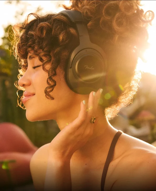 Tai nghe over-ear Fender Mix màu đen, logo Fender trên earcup, người dùng cười vui trước nền họa tiết vòng tròn