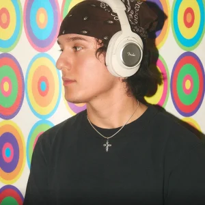 Fender Mix đen đeo ngoài trời buổi chiều, logo vàng trên earcup, ánh sáng lens flare ấm