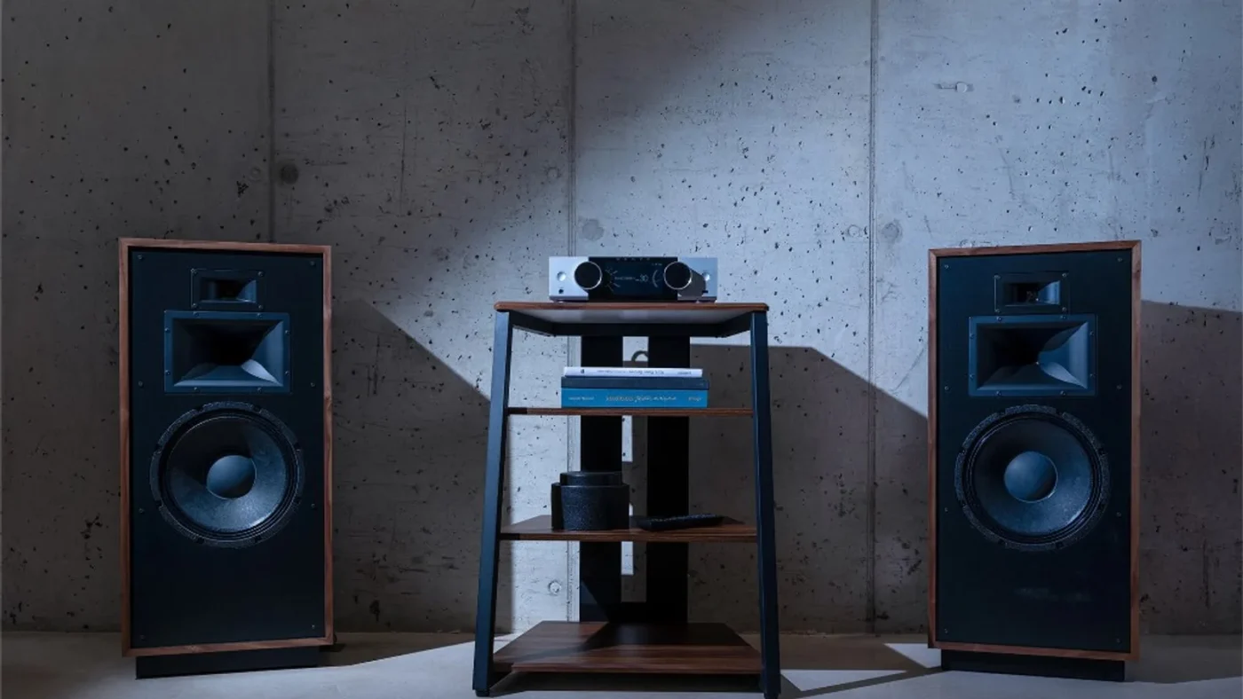 Hệ thống Onkyo Muse Y-40 bạc trên kệ giữa hai loa lớn, ánh sáng kịch tính