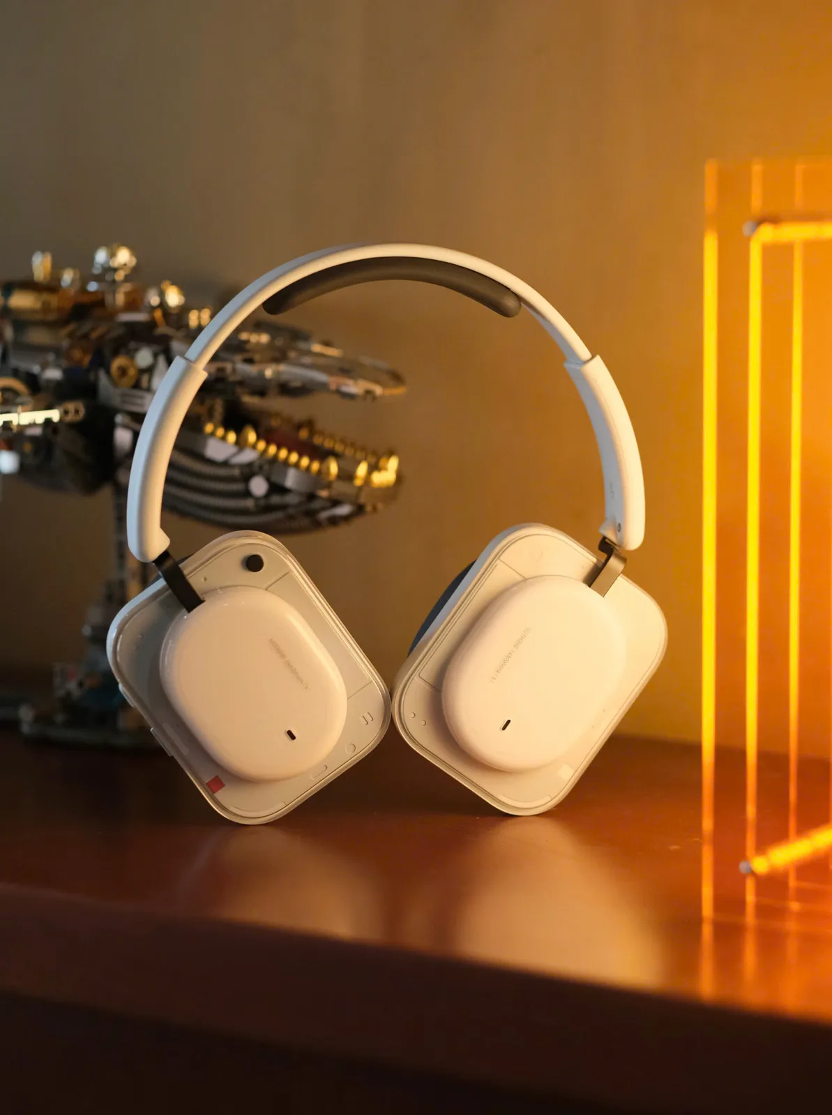 Nothing Headphone (a) màu trắng góc nghiêng trên bàn gỗ, ánh sáng vàng