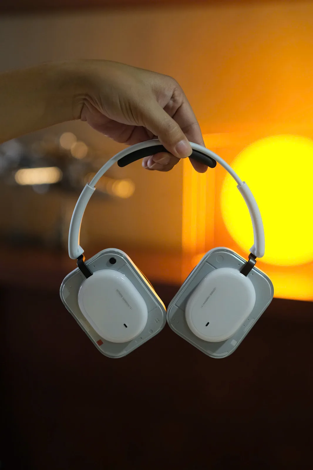 Tay cầm Nothing Headphone (a) màu trắng, nền bokeh ánh sáng vàng District M