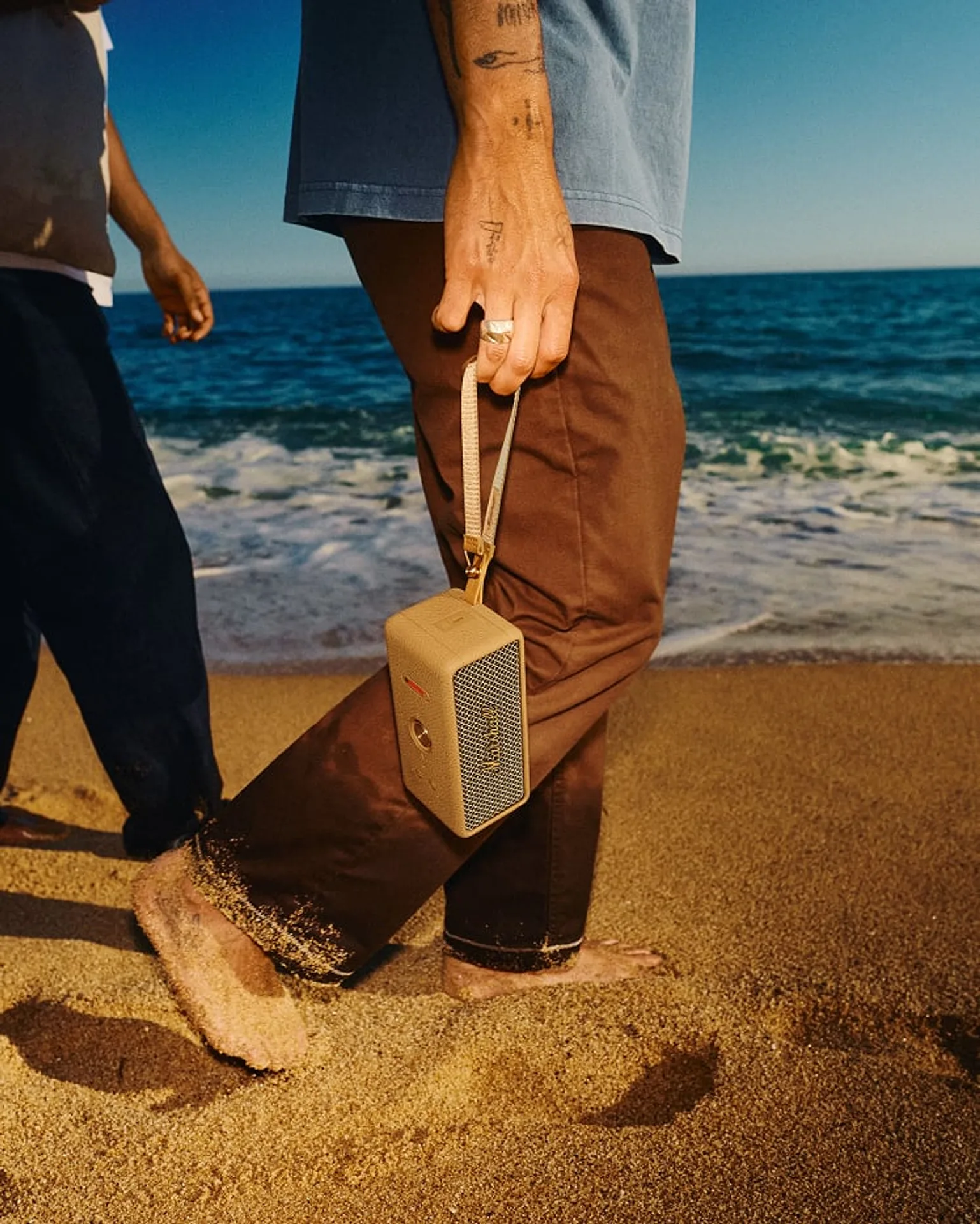 Người mang Marshall Emberton III Brown bằng dây đeo trên bãi biển