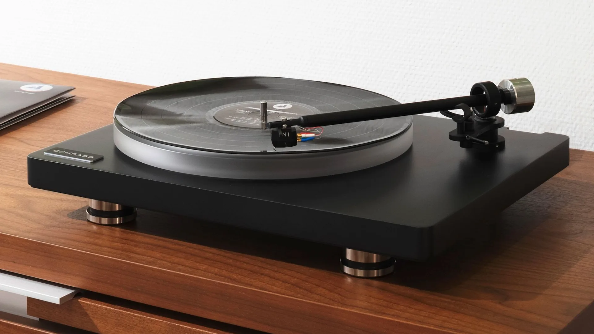Clearaudio Compass màu đen chơi đĩa vinyl trên mặt gỗ, kim N1 hạ trên đĩa