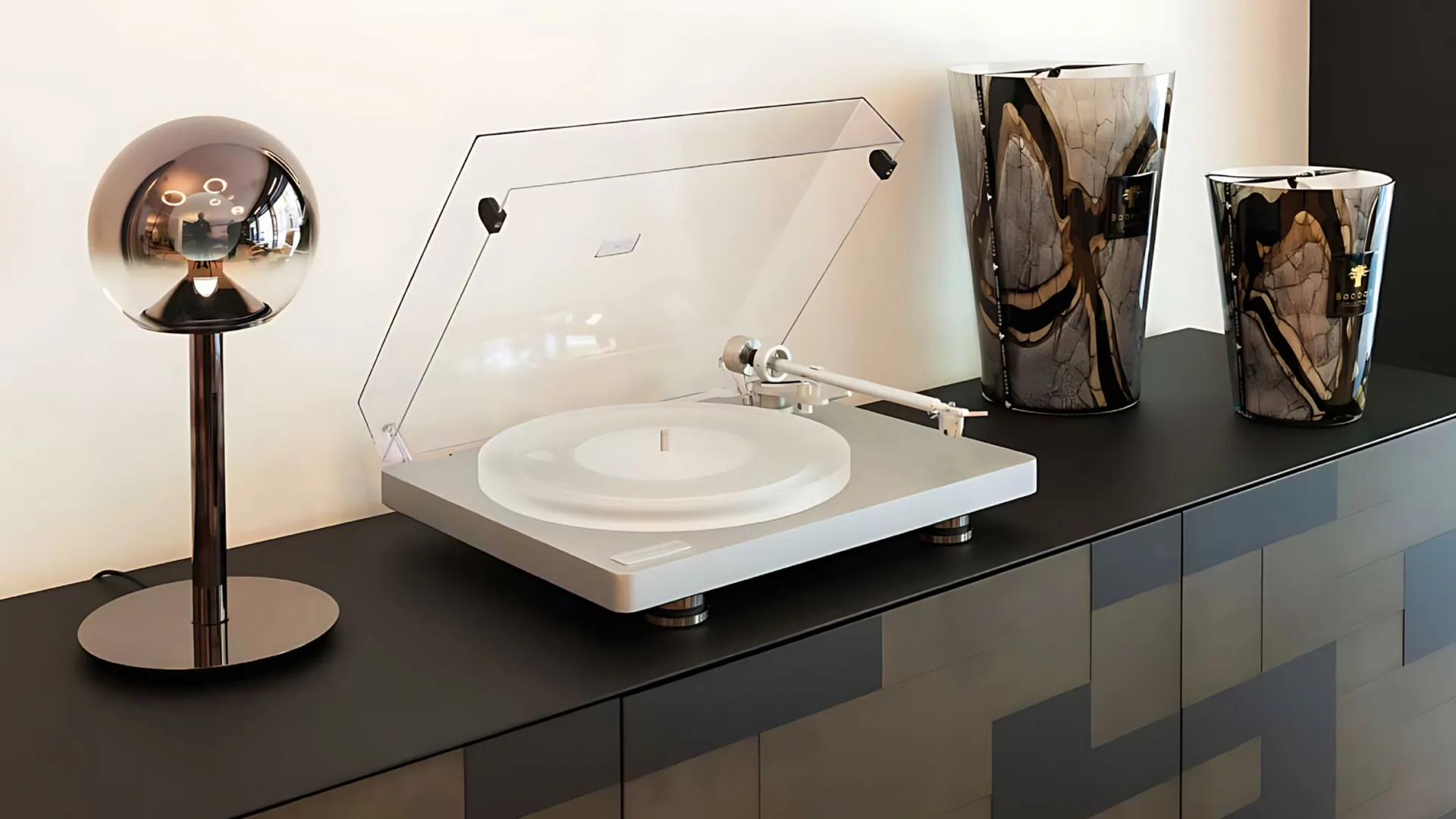 Clearaudio Compass màu trắng trên tủ đen, nắp acrylic mở, đèn chrome và bình trang trí